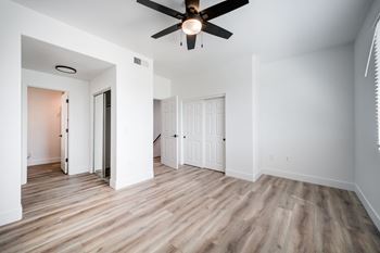 A room with a ceiling fan and wooden flooring.